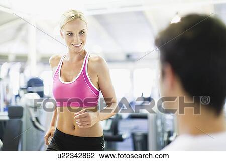 Stock Image - Smiling woman working out in gym. Fotosearch