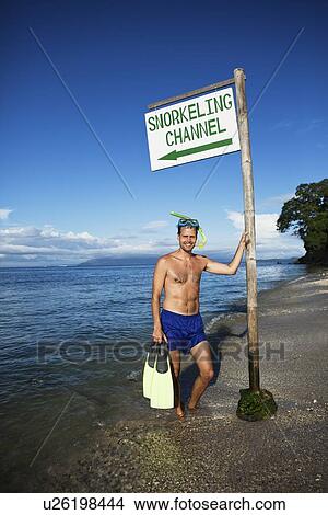 Picture - Snorkeler holding fins on beach. Fotosearch
