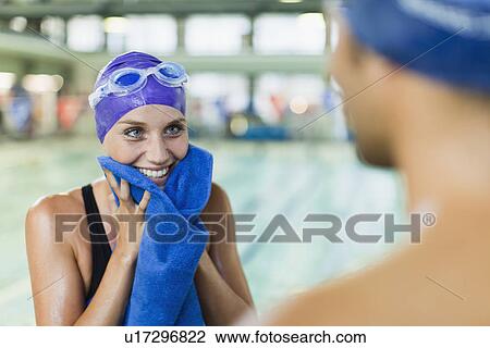 Stock Image - Swimmer toweling off her face by pool. Fotosearch