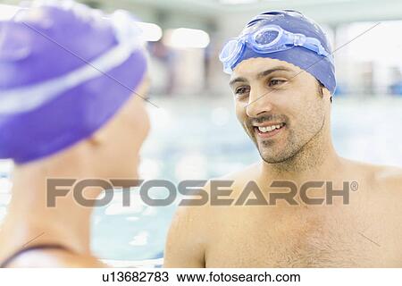 Stock Image - Swimmers talking by pool. Fotosearch