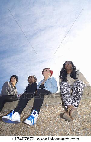Teenagers sitting together on wall View Large Photo Image Stock Image - Teenagers sitting together on wall. Fotosearch
