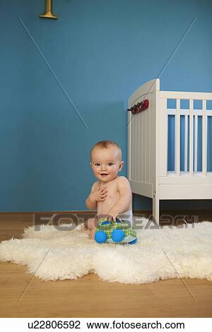 Stock Image - Toddler playing on rug in nursery. Fotosearch