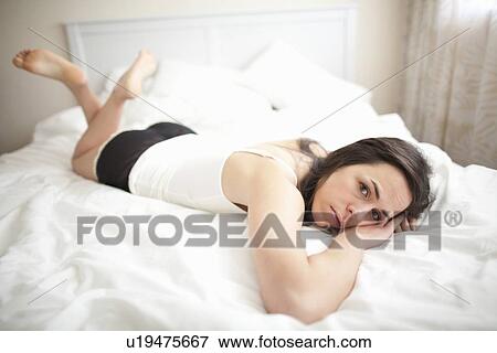 Upset woman lounging in bed View Large Photo Image Stock Photo - Upset woman lounging in bed. Fotosearch