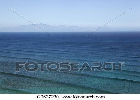 Stock Image - Waves rippling on calm ocean waters. Fotosearch