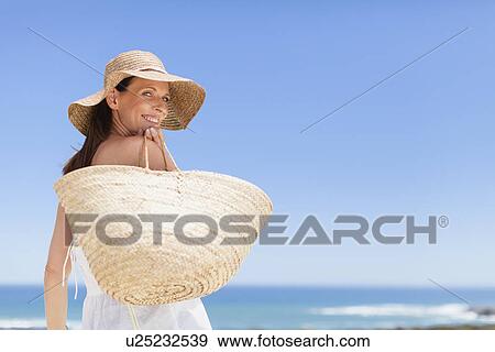 Stock Photo - Woman carrying straw bag outdoors. Fotosearch