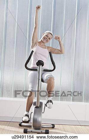 Picture - Woman cheering on exercise machine. Fotosearch