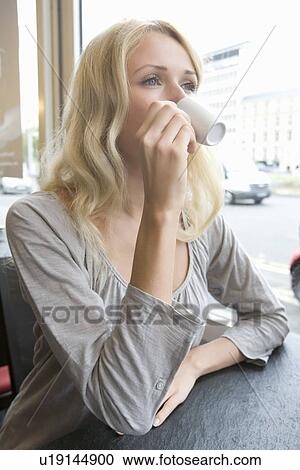 Stock Image - Woman drinking cappuccino in cafe. Fotosearch