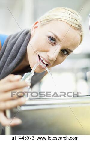 Stock Image - Woman drinking from water fountain. Fotosearch