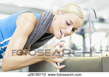 Woman drinking from water fountain View Large Photo Image Stock Image - Woman drinking from water fountain. Fotosearch