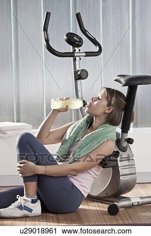 Woman drinking water by exercise machine View Large Photo Image Stock Image - Woman drinking water by exercise machine. Fotosearch