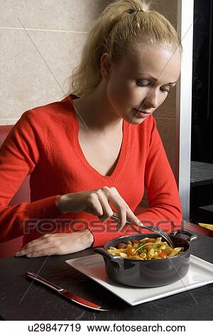 Stock Photo - Woman eating plate of food in cafe. Fotosearch