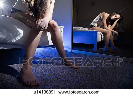 Stock Image - Woman examining herself in mirror. Fotosearch