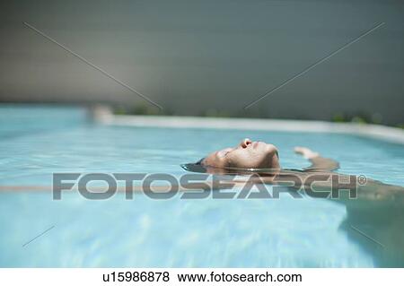Stock Photo - Woman floating in swimming pool. Fotosearch