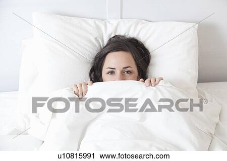 Woman hiding under covers in bed View Large Photo Image Stock Image - Woman hiding under covers in bed. Fotosearch
