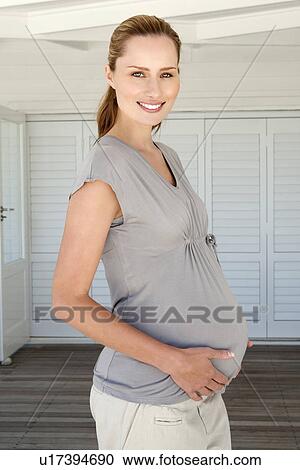 Stock Image - Woman holding pregnant belly. Fotosearch
