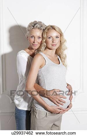 Stock Image - Woman holding pregnant daughters belly. Fotosearch