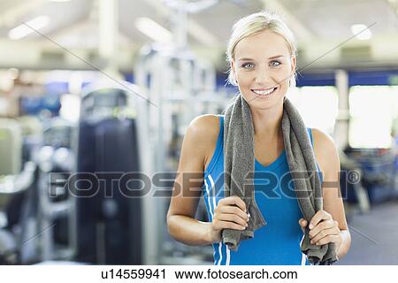 Woman holding towel around neck in gym View Large Photo Image Stock Image - Woman holding towel around neck in gym. Fotosearch