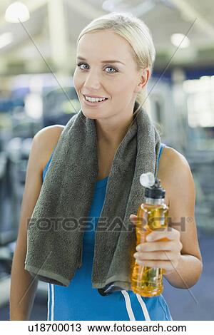 Stock Image - Woman holding water bottle in gym. Fotosearch