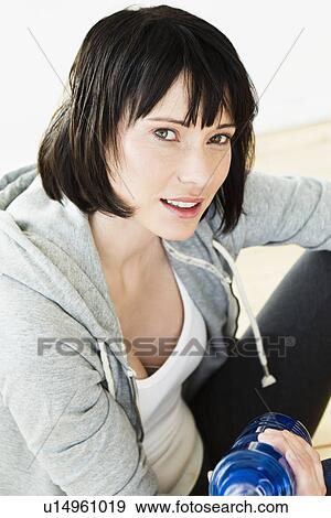 Stock Photo - Woman holding water bottle indoors. Fotosearch