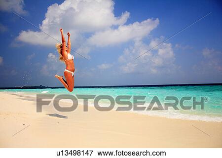 Woman in bikini jumping for joy on beach View Large Photo Image Stock Photo - Woman in bikini jumping for joy on beach. Fotosearch