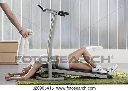 Stock Photography - Woman laying on exercise machine. Fotosearch