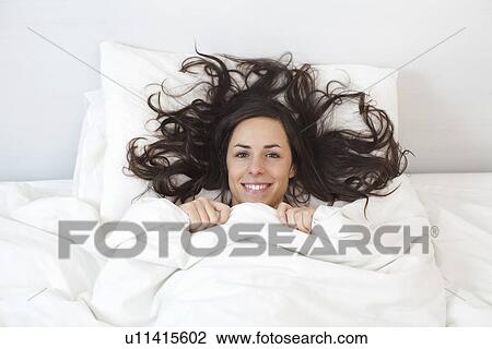Woman laying under covers in bed View Large Photo Image Stock Image - Woman laying under covers in bed. Fotosearch
