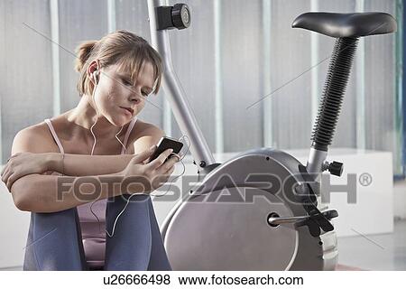Woman listening to headphones in gym View Large Photo Image Stock Photo - Woman listening to headphones in gym. Fotosearch