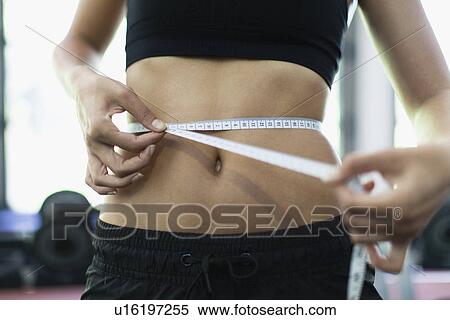 Stock Photography - Woman measuring waist in gym. Fotosearch