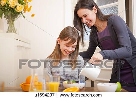 Woman pouring milk for daughter at table View Large Photo Image Stock Image - Woman pouring milk for daughter at table. Fotosearch
