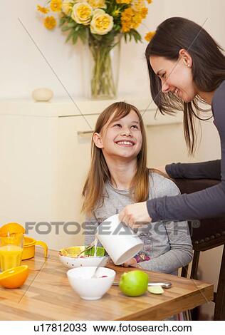Woman pouring milk for daughter at table View Large Photo Image Stock Image - Woman pouring milk for daughter at table. Fotosearch