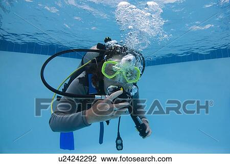 Stock Image - Woman practicing scuba diving in pool. Fotosearch