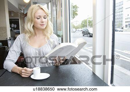 Stock Image - Woman reading book in cafe. Fotosearch