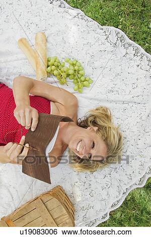 Woman reading book on picnic blanket View Large Photo Image Stock Photograph - Woman reading book on picnic blanket. Fotosearch