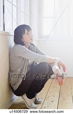 Stock Photo - Woman resting against wall in studio. Fotosearch