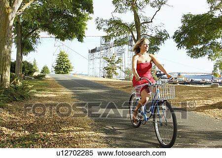 Stock Photography - Woman riding bicycle on rural road. Fotosearch