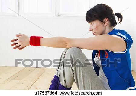 Picture - Woman sitting on floor after workout. Fotosearch