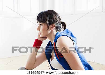 Stock Photo - Woman sitting on floor after workout. Fotosearch