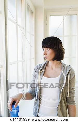 Stock Photo - Woman standing at window. Fotosearch
