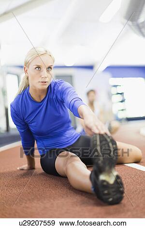 Stock Photo - Woman stretching on indoor track in gym. Fotosearch