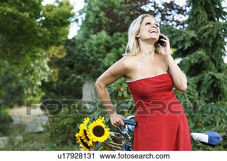 Woman talking on cell phone on bicycle View Large Photo Image Stock Image - Woman talking on cell phone on bicycle. Fotosearch