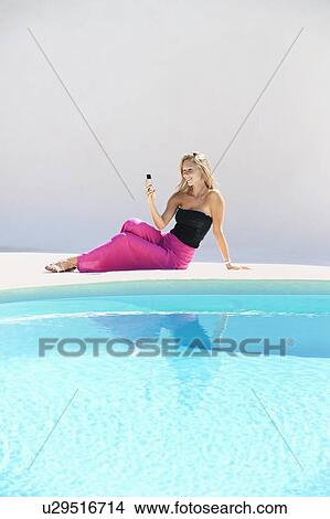 Woman using cell phone by pool View Large Photo Image Picture - Woman using cell phone by pool. Fotosearch