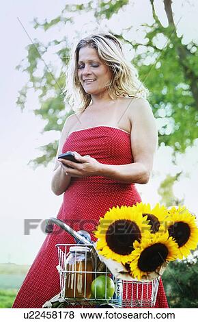 Woman using cell phone on bicycle View Large Photo Image Stock Photo - Woman using cell phone on bicycle. Fotosearch