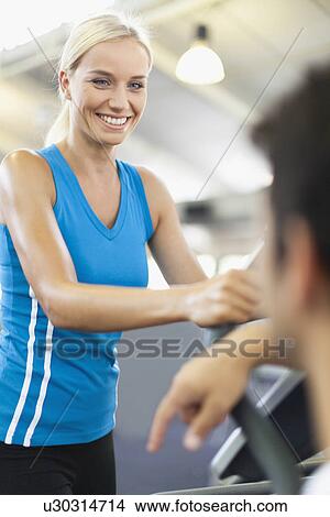 Picture - Woman using exercise machine in gym. Fotosearch