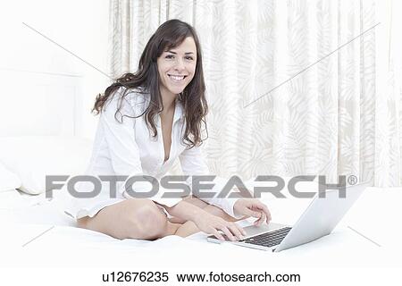 Woman using laptop on bed View Large Photo Image Stock Photography - Woman using laptop on bed. Fotosearch