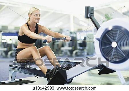 Woman using rowing machine in gym View Large Photo Image Stock Image - Woman using rowing machine in gym. Fotosearch