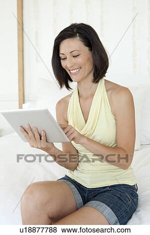 Woman using tablet computer on sofa View Large Photo Image Stock Photo - Woman using tablet computer on sofa. Fotosearch