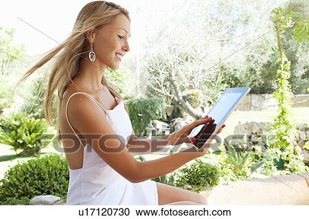 Stock Image - Woman using tablet computer outdoors. Fotosearch