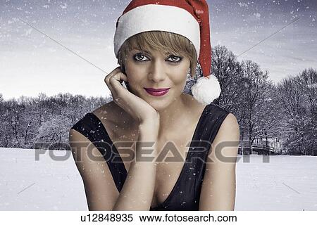 Stock Photography - Woman wearing Santa hat in snow. Fotosearch
