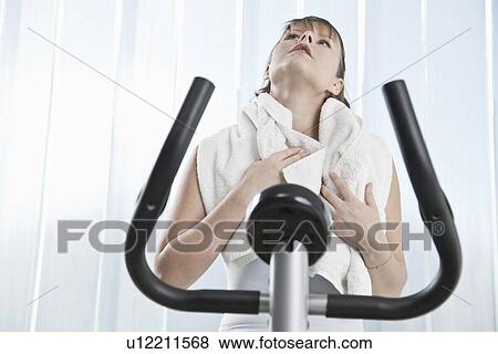 Woman wiping sweat on exercise machine View Large Photo Image Stock Photo - Woman wiping sweat on exercise machine. Fotosearch