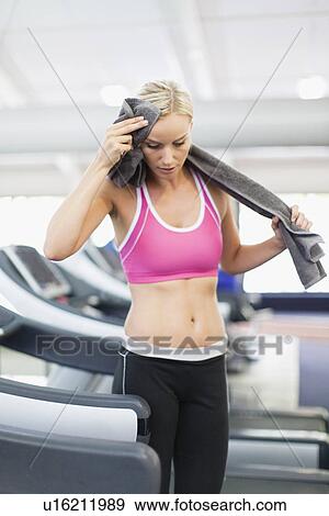 Stock Photo - Woman wiping sweat on exercise machine. Fotosearch